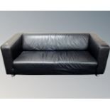 A pair of contemporary black leather settees on metal legs.