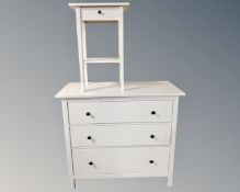A white IKEA three drawer chest together with two tier bedside table fitted with a drawer.