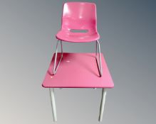 A square pink topped dining table on metal legs together with matching chair.