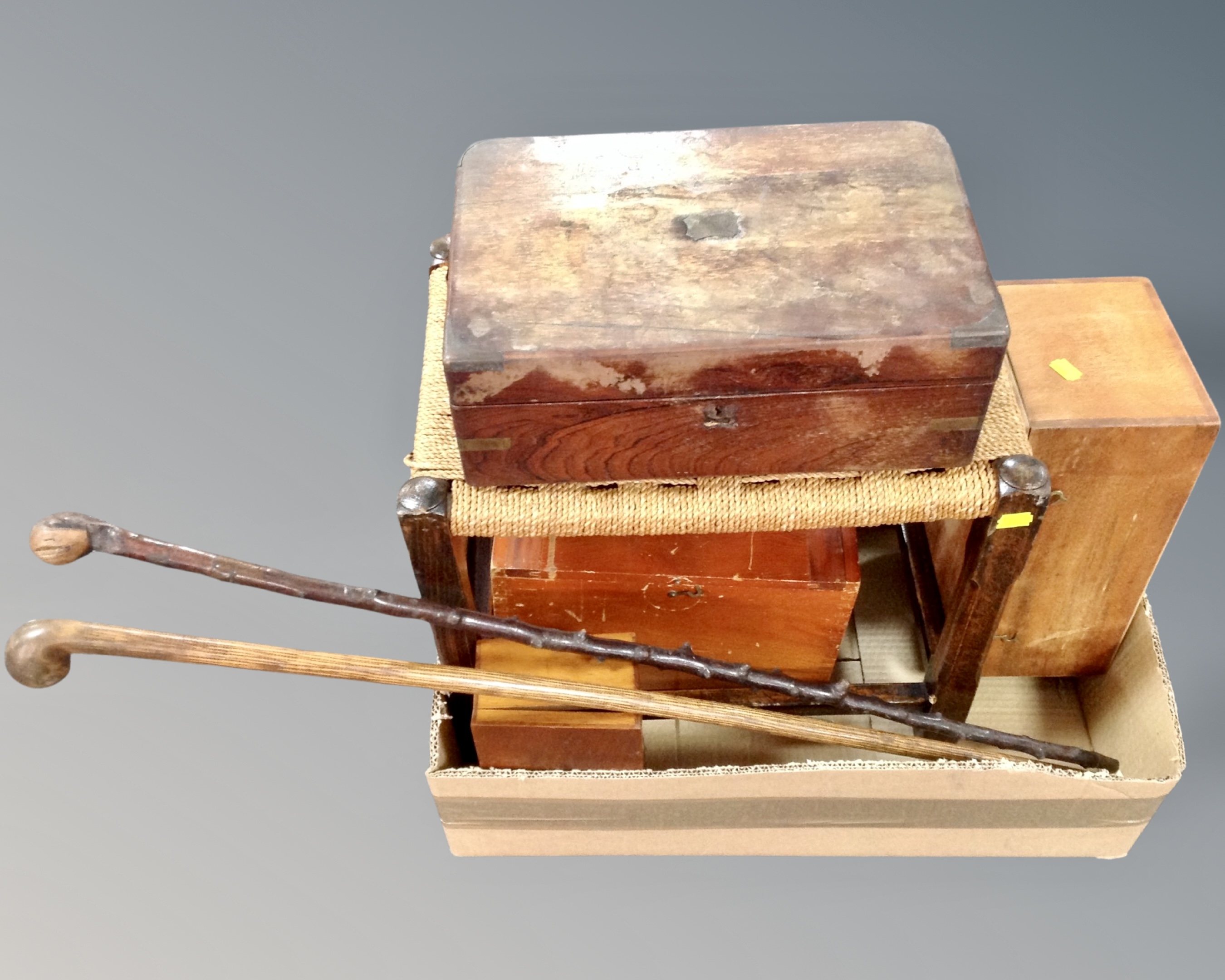A box containing antique and later table boxes together with a rush seated stool and two walking