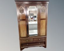 An Edwardian mahogany mirror door wardrobe fitted with three drawers beneath.