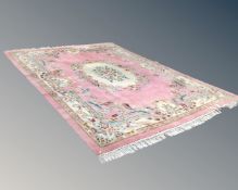A Chinese fringed embossed carpet on pink ground.