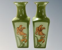 A pair of studio pottery vases decorated with flowers.