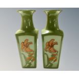 A pair of studio pottery vases decorated with flowers.