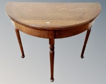 An Edwardian oak D-shaped turnover top card table.