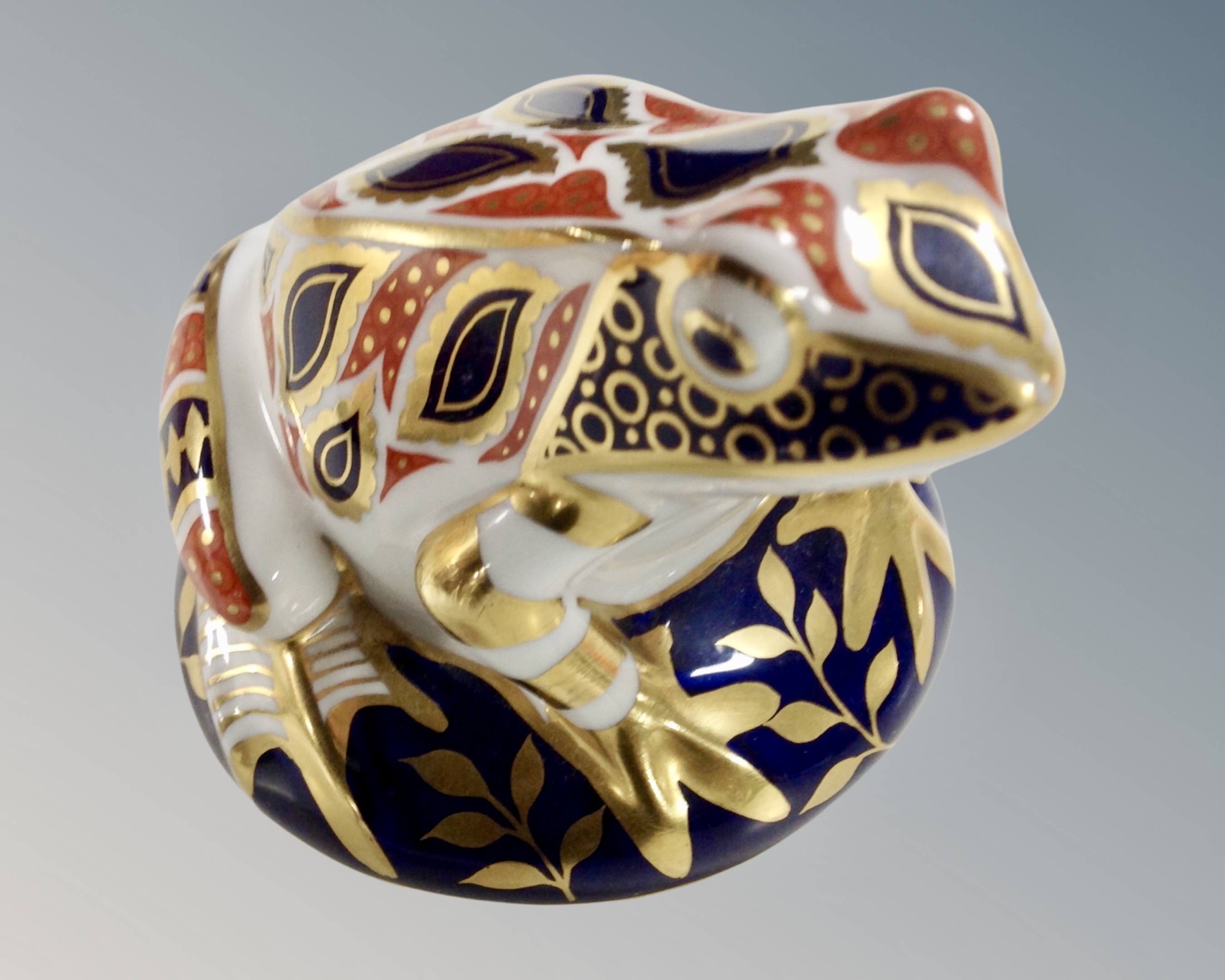 A Royal Crown Derby frog paperweight with silver stopper.