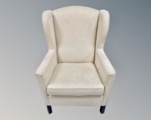 A Scandinavian late 20th century wing backed armchair in cream fabric ,