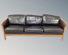 A Scandinavian wooden framed black leather three seater settee,