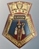 A painted cast iron Glasgow plaque mounted on wooden board.