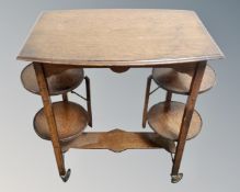 An oak tea table fitted with cake stands beneath, on castors.