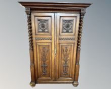 A late 19th century Scandinavian heavily carved oak two door cabinet with barleytwist supports and