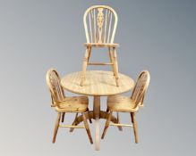 A contemporary circular dining table together with a set of three pine wheelback chairs.