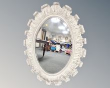 A large oval hall mirror in cream swept frame, 128cm by 98cm.