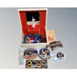 A musical jewellery box containing costume beads, model cannon, Apollo 11 patches etc.