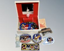 A musical jewellery box containing costume beads, model cannon, Apollo 11 patches etc.