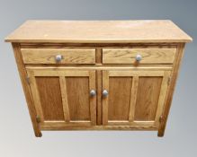 A contemporary oak sideboard with cupboards and drawers beneath,