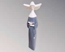 A Lladro figure of a nun reading.