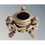 A circular brass bowl supported by three winged cherubs, height 9.