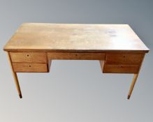 A continental teak writing desk fitted with five drawers.