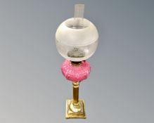 A brass oil lamp with opaque pink glass reservoir and etched glass shade CONDITION