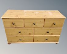 A contemporary pine effect seven drawer chest, width 123 cm.