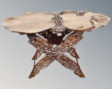 An Asian hardwood heavily carved occasional table with lift off tray