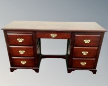 A twin pedestal knee hole dressing table fitted with seven drawers and brass drop handles in