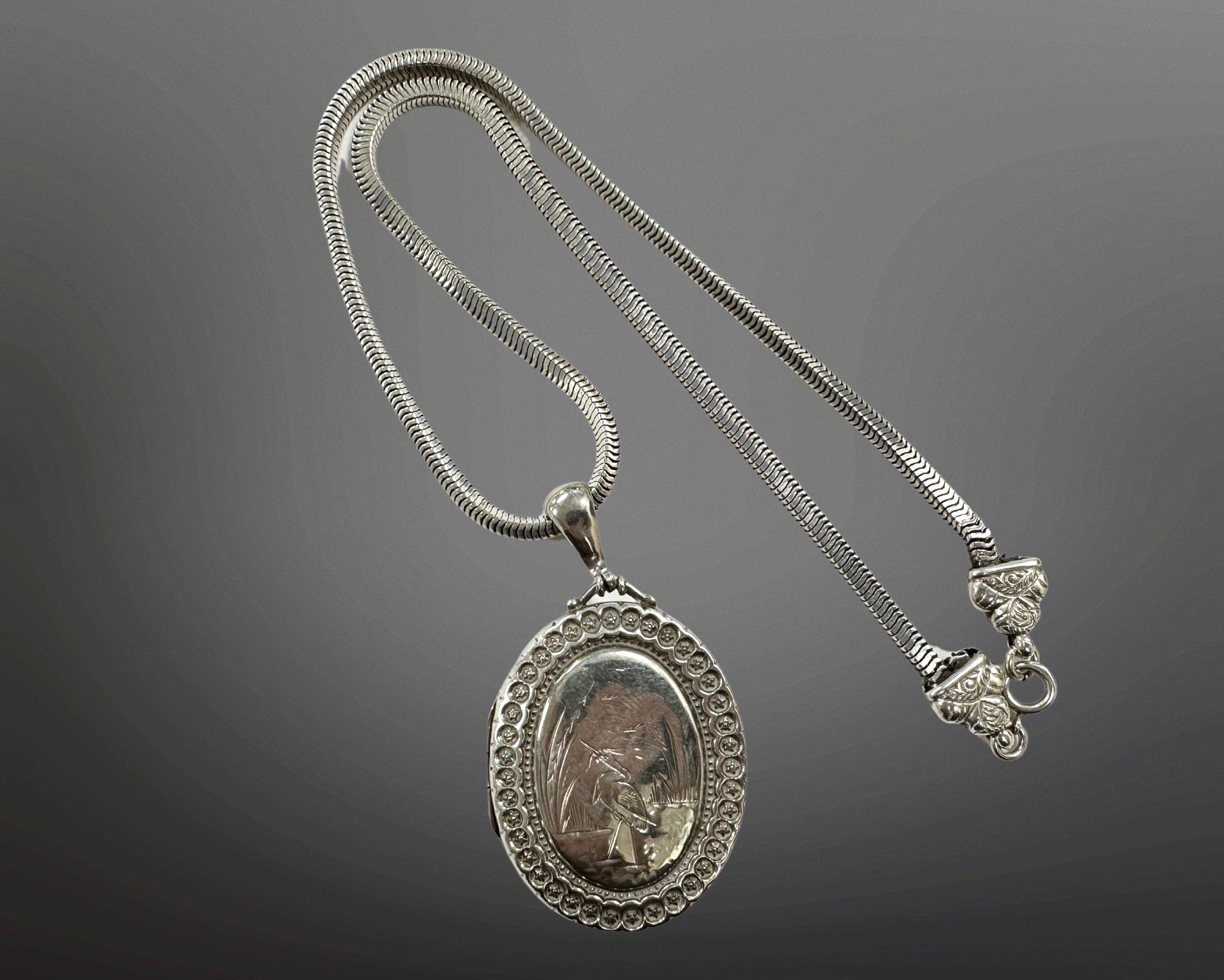 A silver locket on articulated necklace with ornate clasp, length 44cm.
