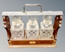 An early 20th century inlaid mahogany and chrome mounted Tantalus with three glass decanters.