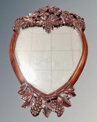 A carved Asian hardwood heart-shaped bevelled mirror of grape design