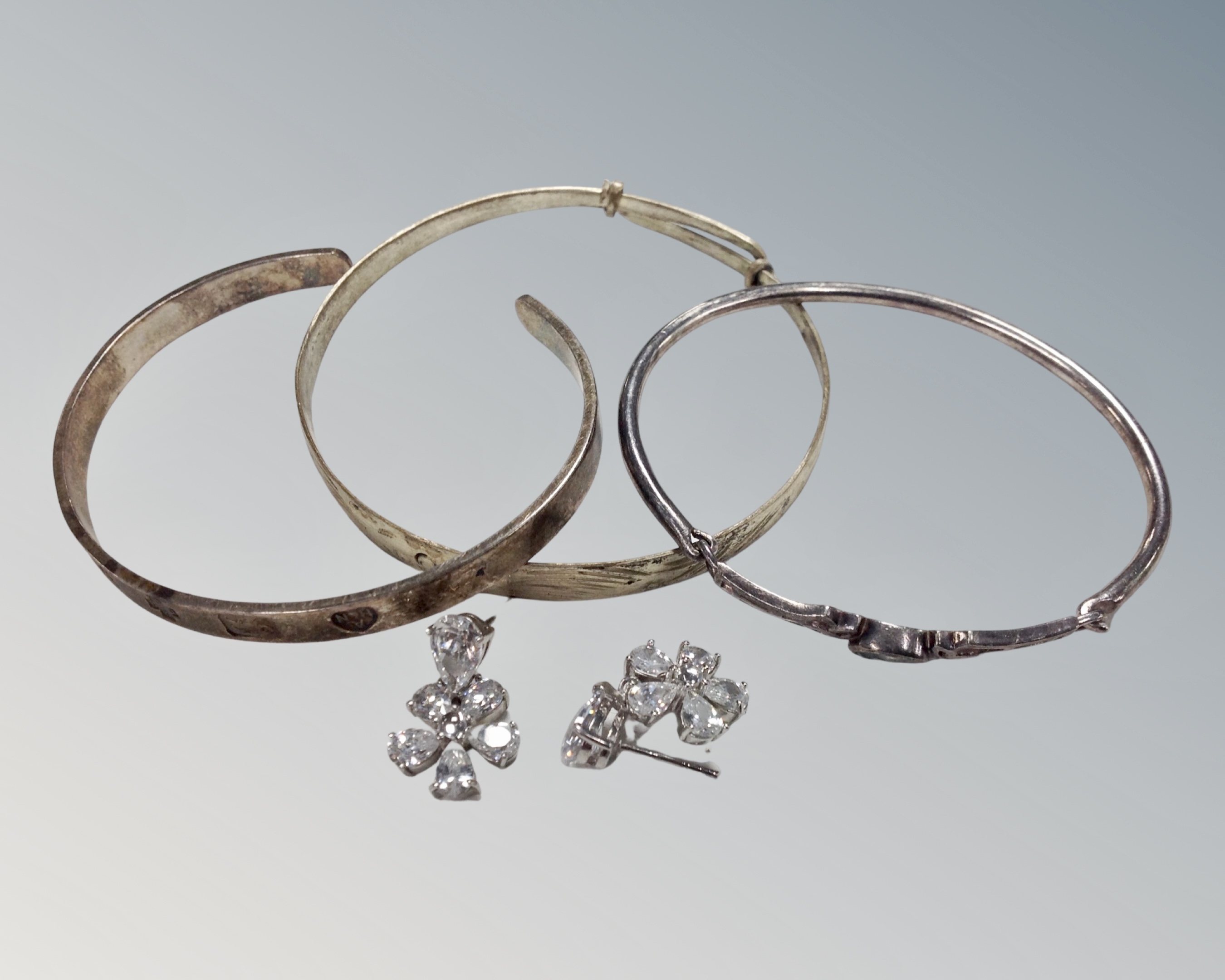 Three silver bracelets together with a pair of silver diamonte earrings.