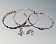 Three silver bracelets together with a pair of silver diamonte earrings.