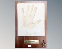 A Muhammed Ali hand imprint plaque mounted on a board.