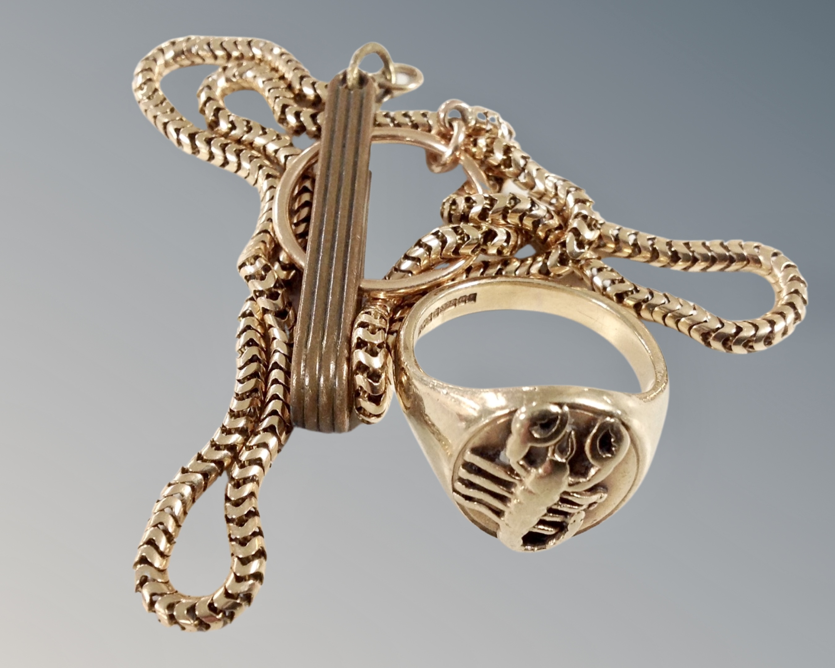 A gent's heavy gauge 9ct gold signet ring embossed with a scorpion together with a gilt chain.