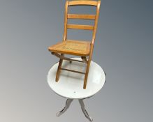 A glass topped circular table and a cane-seated folding chair.