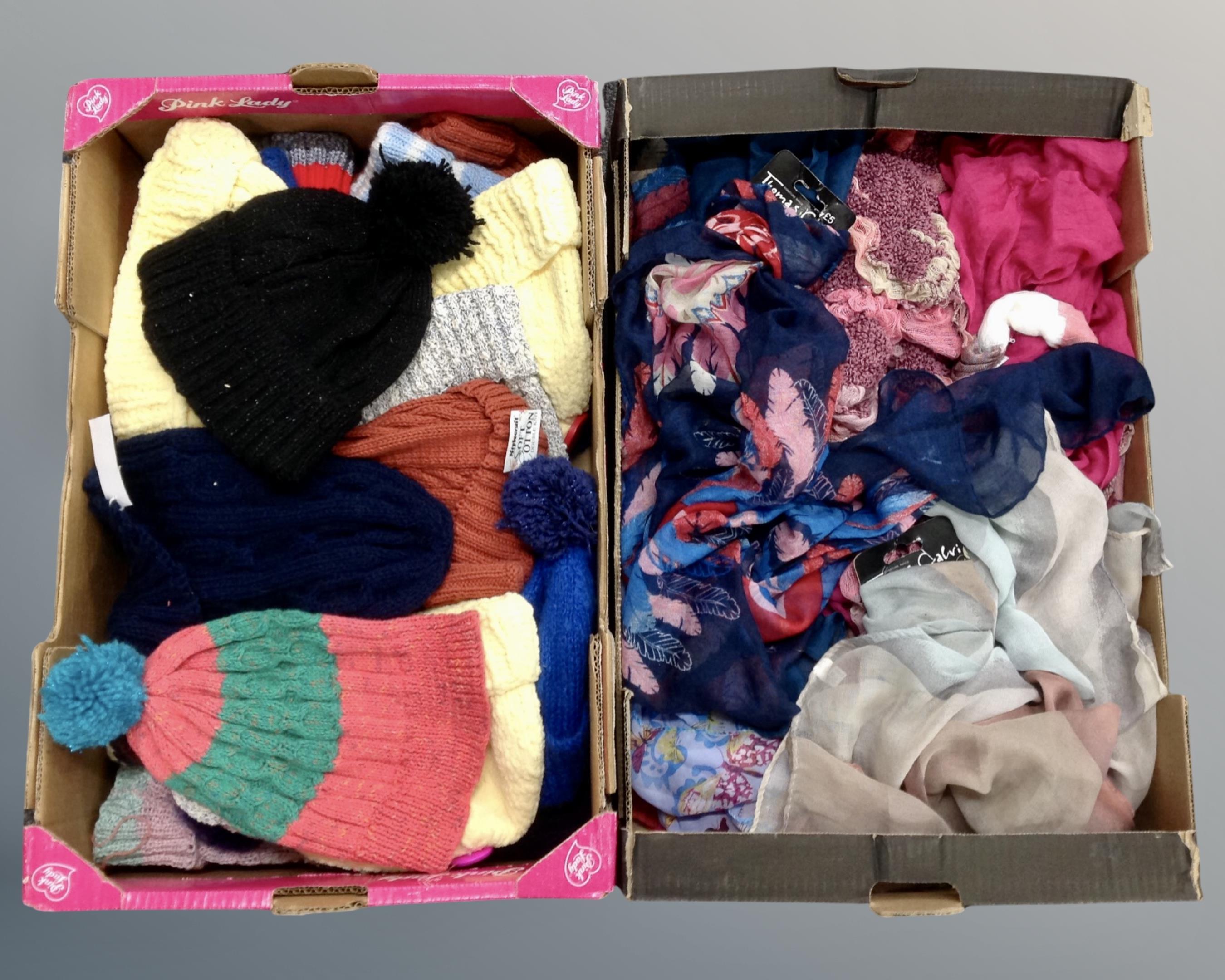 Two boxes containing lady's scarves and woolen bobble hats.