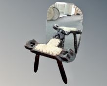 A frameless mirror together with a tripod stool.