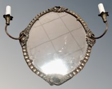 A metal framed oval twin sconce wall mirror.