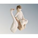 A Lladro figure of a boy sat on a tree stump and a further Lladro goose.