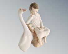 A Lladro figure of a boy sat on a tree stump and a further Lladro goose.