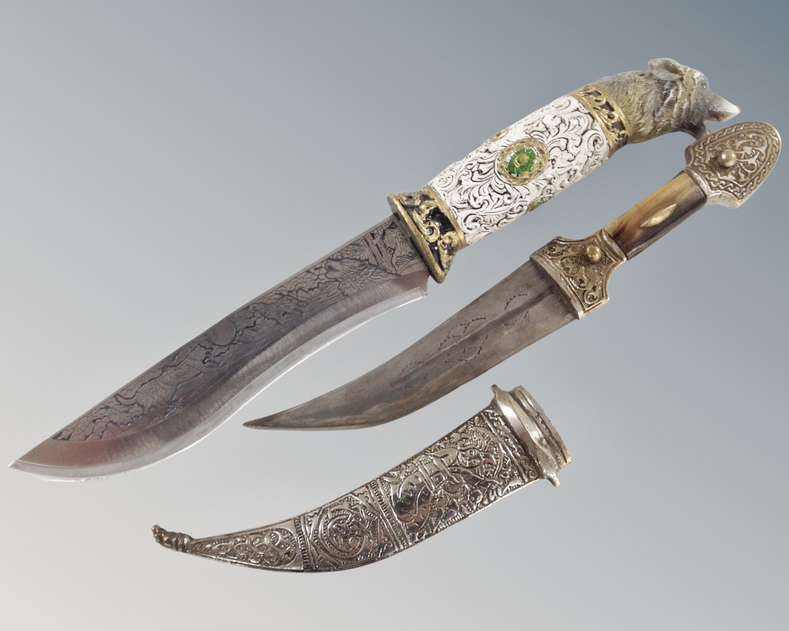 A large hunting knife with etched wolf decoration and wolf head handle together with an Eastern