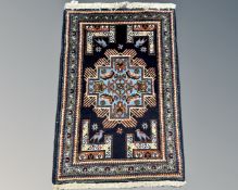 A fringed Caucasian rug with geometric design on blue ground, 110cm by 71cm.