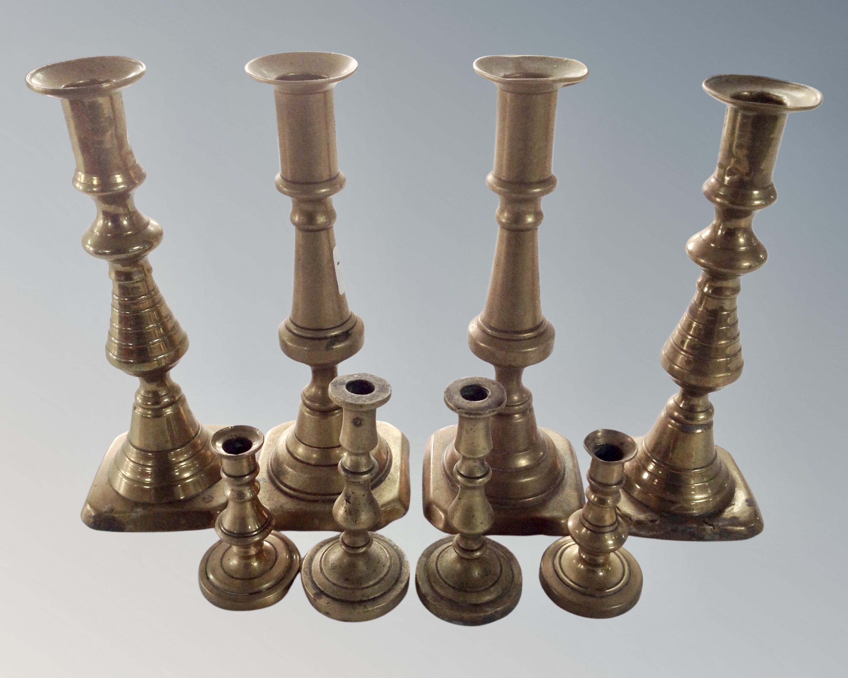 Four pairs of brass candlesticks.