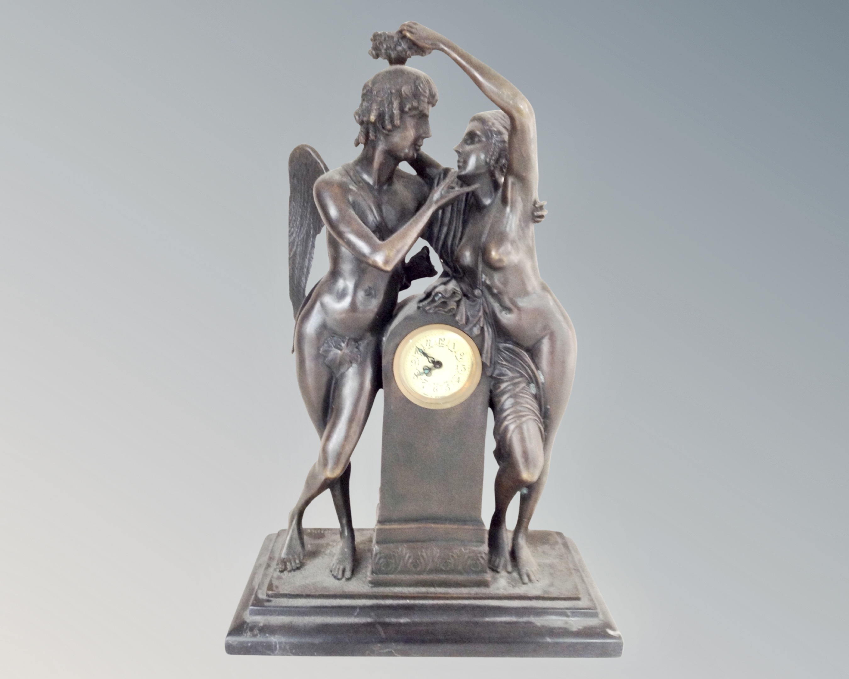 An Art Nouveau style patinated metal mantel clock on black marble base.