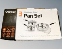 A boxed three piece stainless steel pan set with lids.