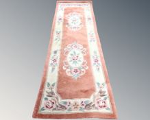 A Chinese embossed carpet runner on peach ground.