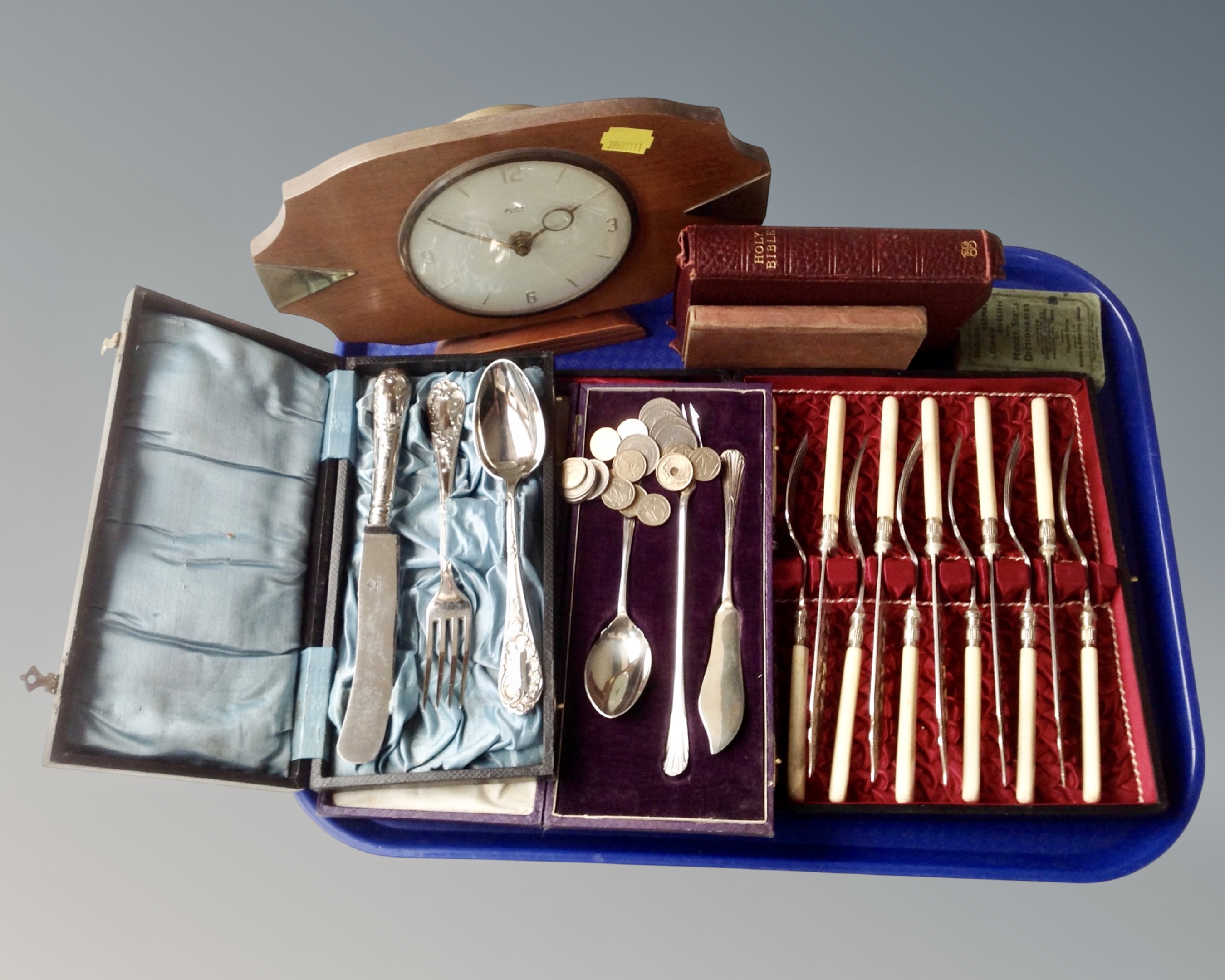 A tray containing boxed cutlery sets, Bentima teak eight day mantel clock, Holy Bible, coins etc.