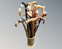 A brass embossed stick stand containing a collection of walking sticks.