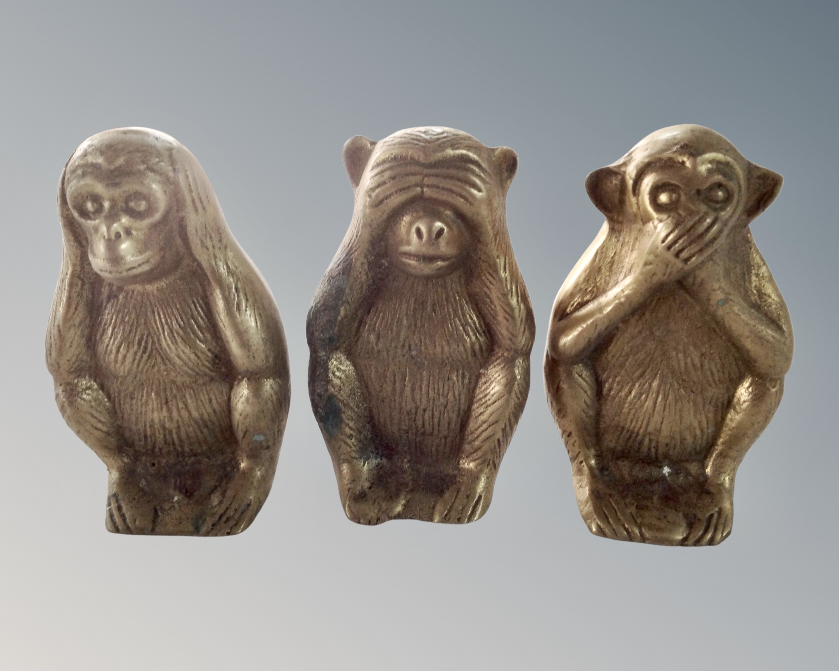 Three cast brass seated monkey figures.