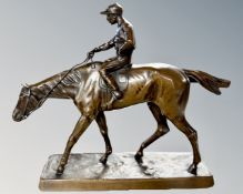 A bronzed metal figure of a jockey on horseback, length 27cm.